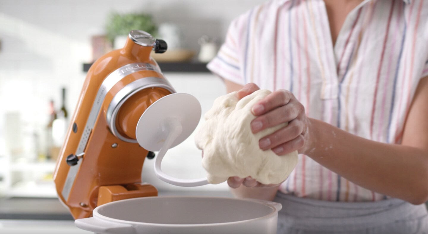 Person taking dough off of dough hook Person taking dough off of dough hook