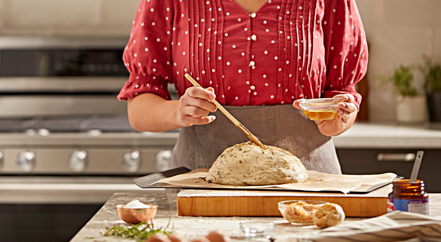 Person brushing egg on bread dough Person brushing egg on bread dough