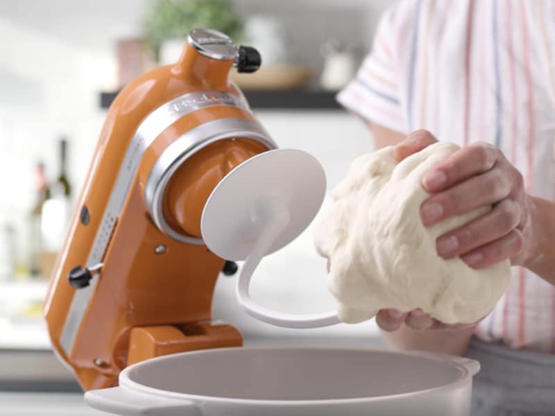 Person taking dough off of dough hook Person taking dough off of dough hook