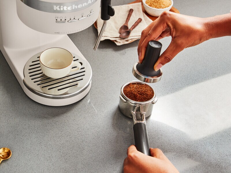 Person tamping espresso in a portafilter