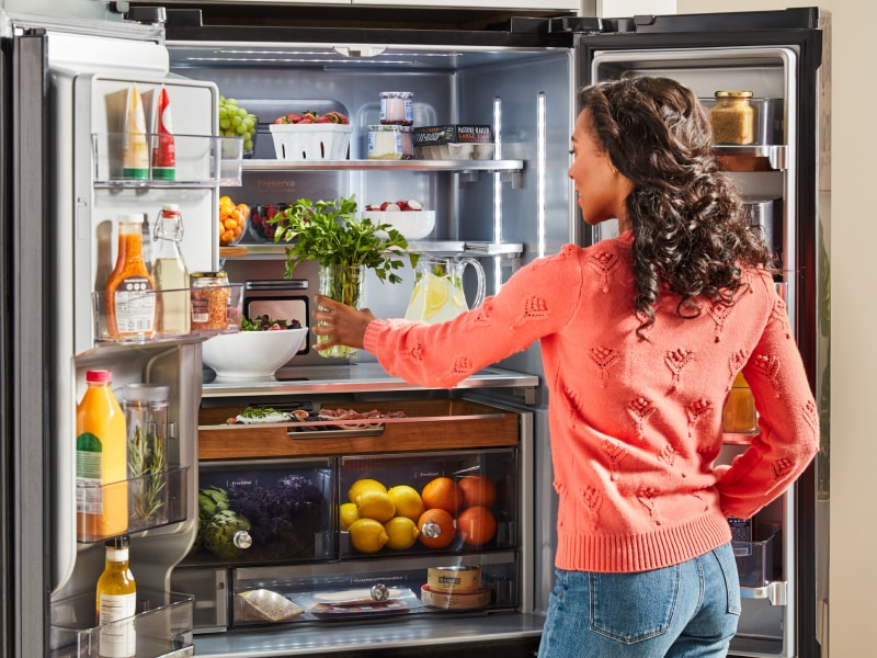 Person placing fresh herbs inside a French door refrigerator