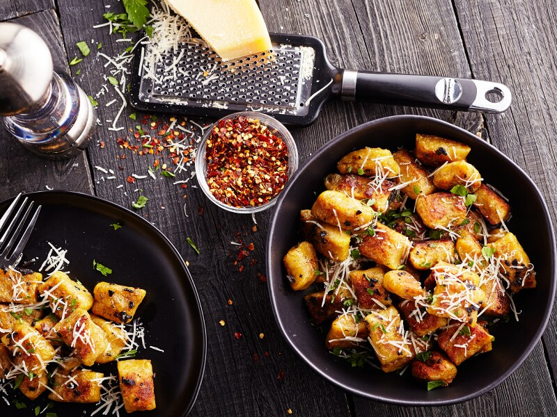 Two bowls of potato gnocchi meals with fresh parmesan, red pepper flakes and herbs.  Two bowls of potato gnocchi meals with fresh parmesan, red pepper flakes and herbs.