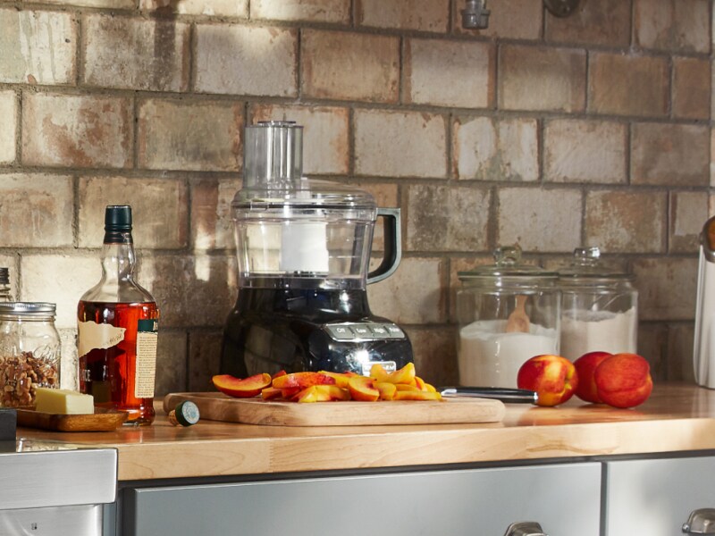 Sliced peaches on counter with ingredients and food processor Sliced peaches on counter with ingredients and food processor