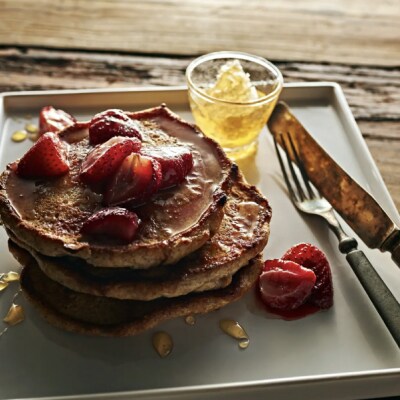 Homemade pancakes on tray topped with fresh strawberries