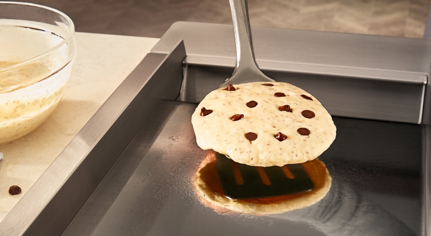 Person flipping chocolate chip pancake with spatula Person flipping chocolate chip pancake with spatula