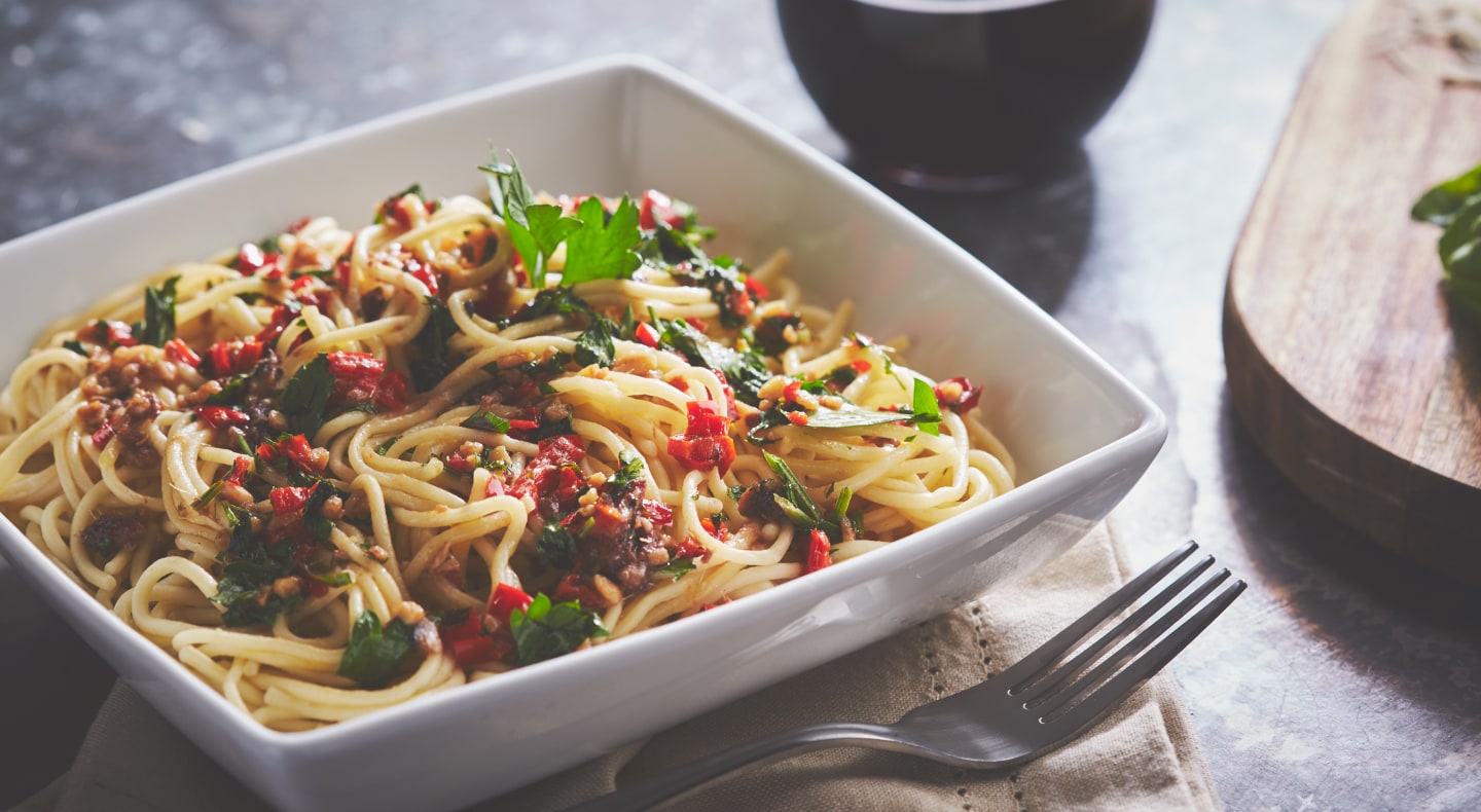Homemade pasta in square white bowl topped with colorful sauce Homemade pasta in square white bowl topped with colorful sauce