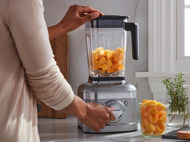 Person blending pumpkin in a KitchenAid® blender