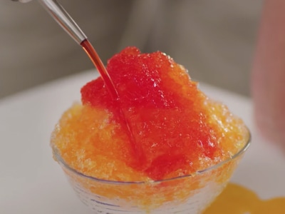 Syrup being poured on shave ice