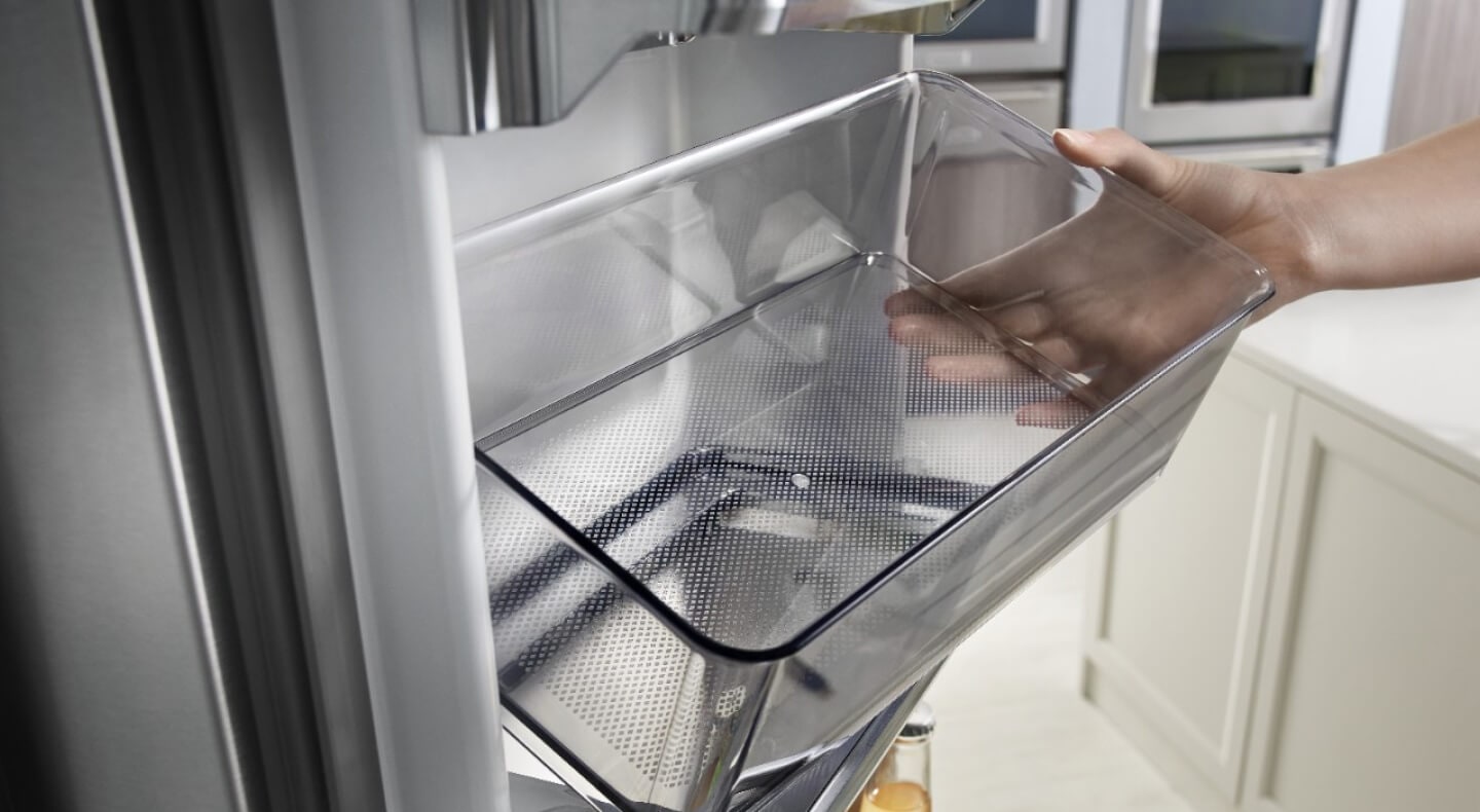 Person removing a storage bin from a refrigerator Person removing a storage bin from a refrigerator