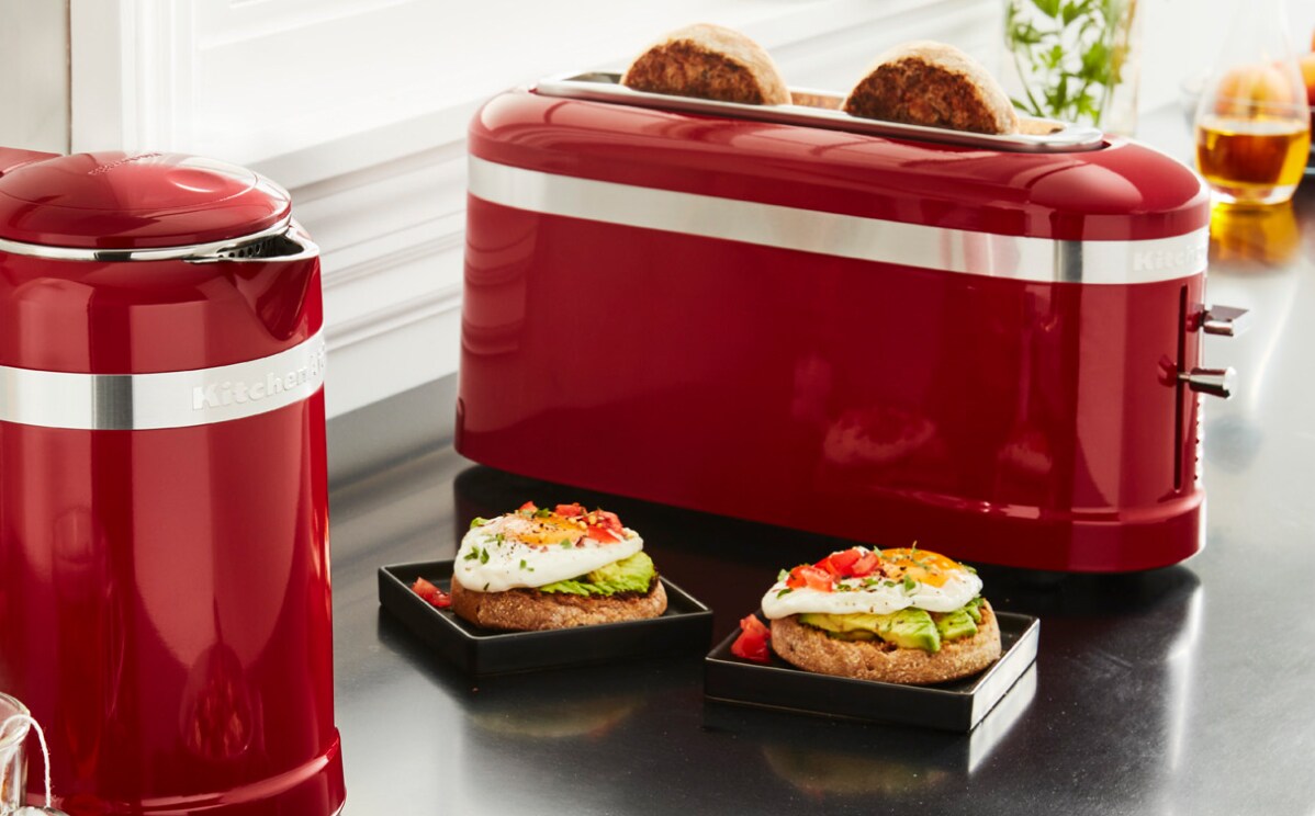 Two poached eggs on English muffins on a countertop next to various kitchen appliances