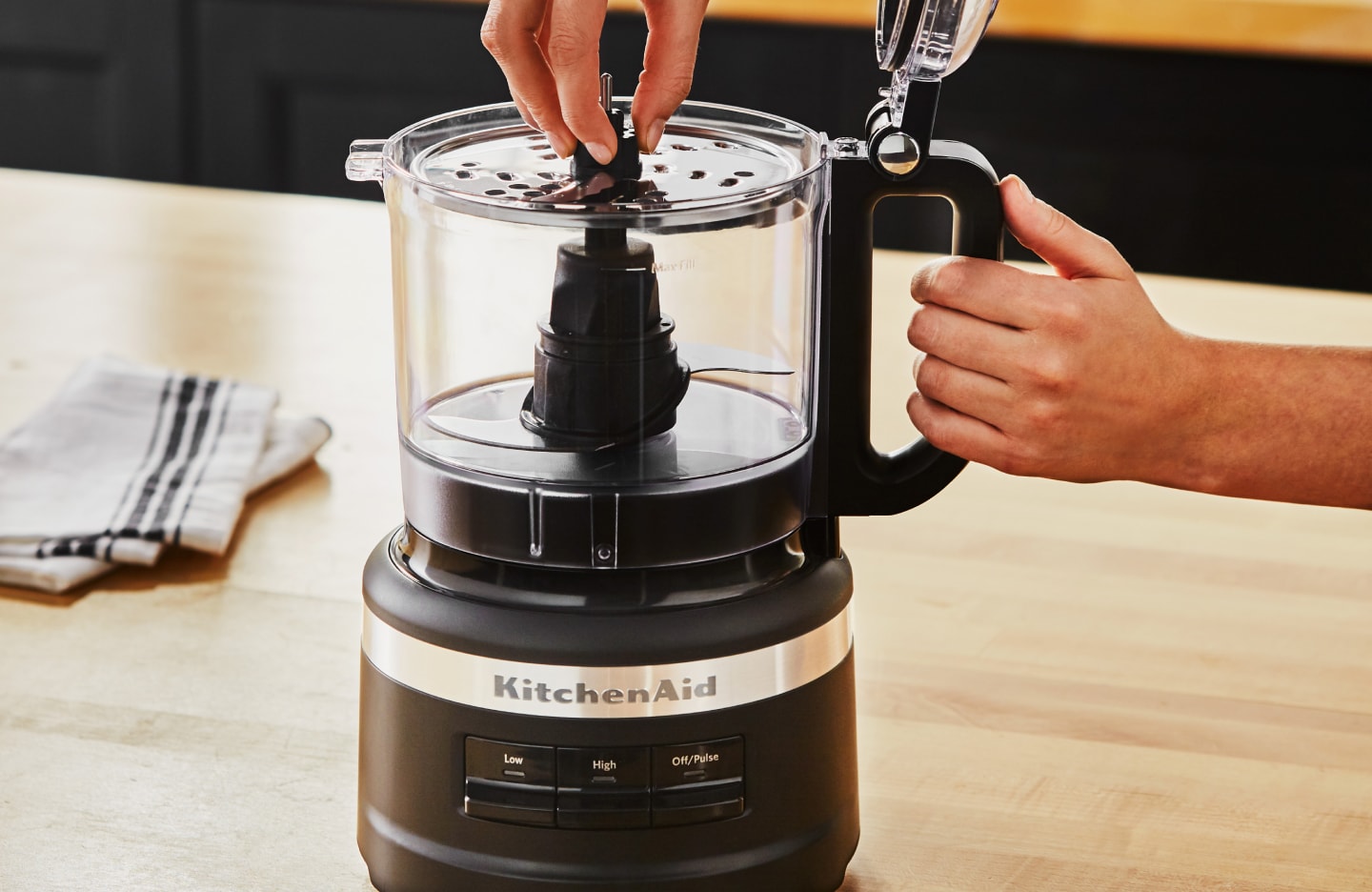 A woman putting a blade into a KitchenAid® food processor A woman putting a blade into a KitchenAid® food processor
