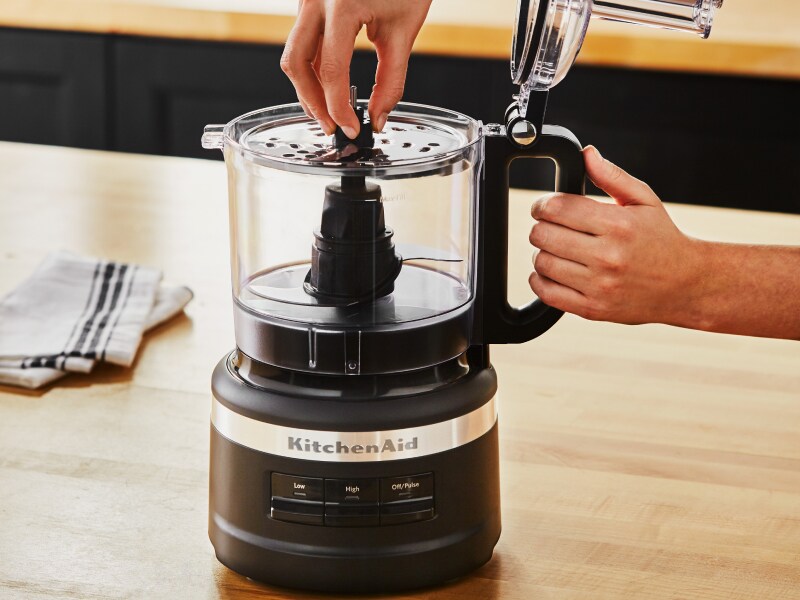 A woman putting a blade into a KitchenAid® food processor A woman putting a blade into a KitchenAid® food processor