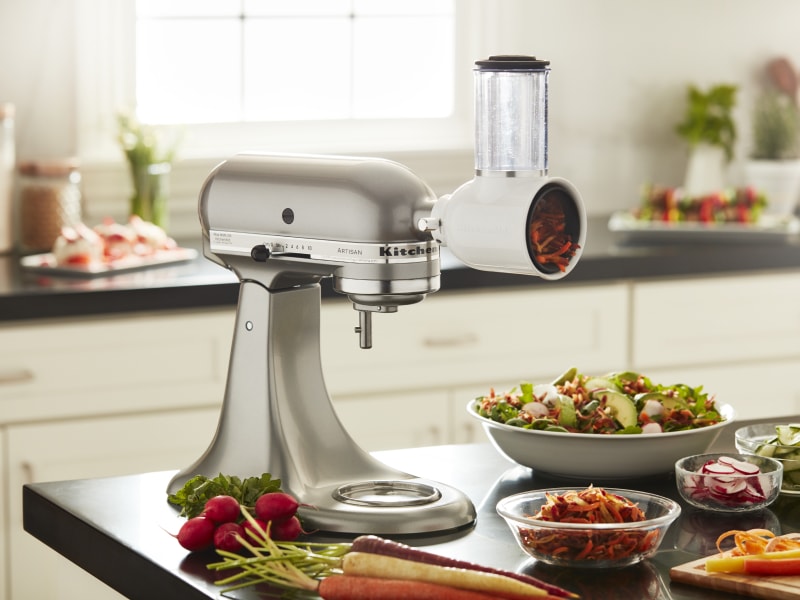 KitchenAid® stand mixer with a fresh prep slicer/shredder attachment in a modern kitchen next to freshly sliced vegetables KitchenAid® stand mixer with a fresh prep slicer/shredder attachment in a modern kitchen next to freshly sliced vegetables