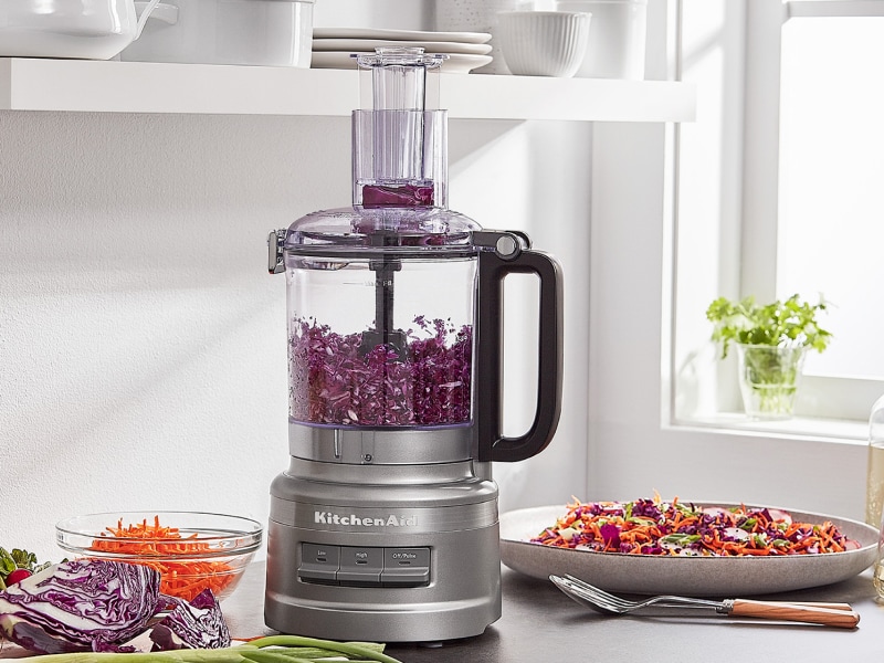 Shredded purple cabbage in a KitchenAid® food processor on a kitchen counter next to a plate of food Shredded purple cabbage in a KitchenAid® food processor on a kitchen counter next to a plate of food