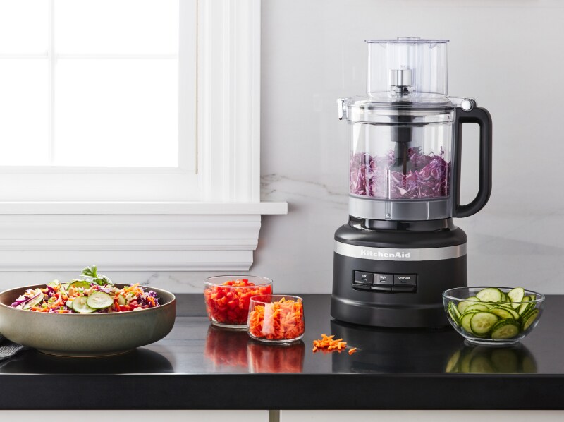 Shredded purple cabbage in a KitchenAid® food processor on a kitchen counter next to other shredded vegetables Shredded purple cabbage in a KitchenAid® food processor on a kitchen counter next to other shredded vegetables