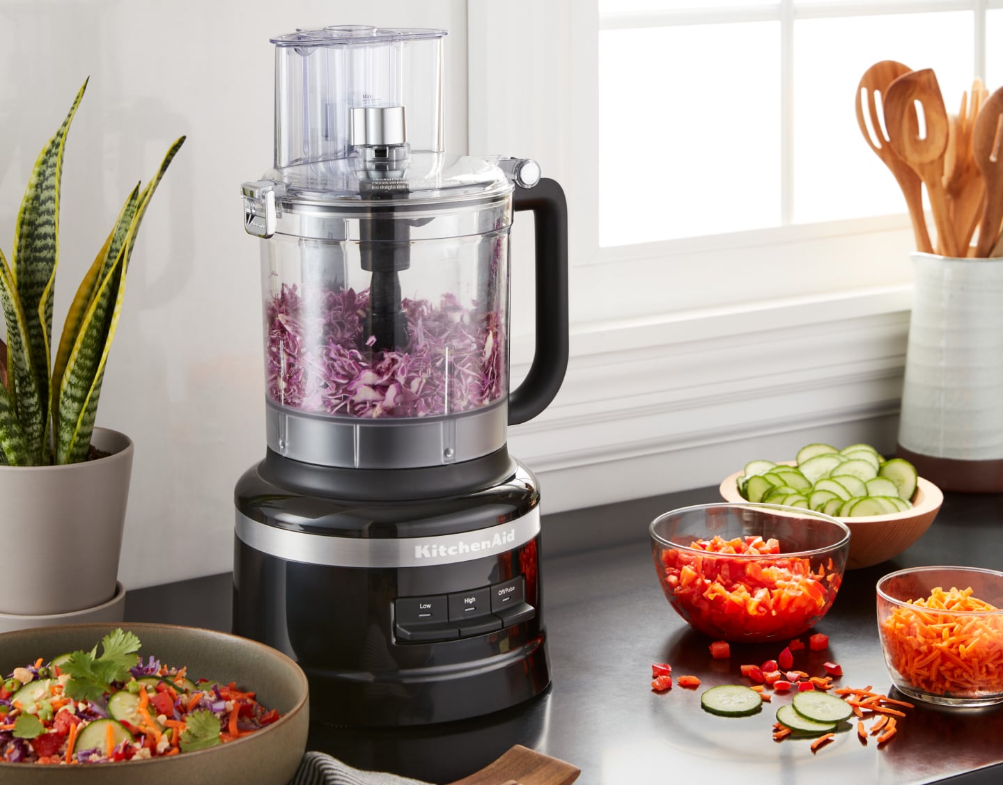 Shredded purple cabbage in a KitchenAid® food processor on a kitchen counter next to other shredded vegetables Shredded purple cabbage in a KitchenAid® food processor on a kitchen counter next to other shredded vegetables