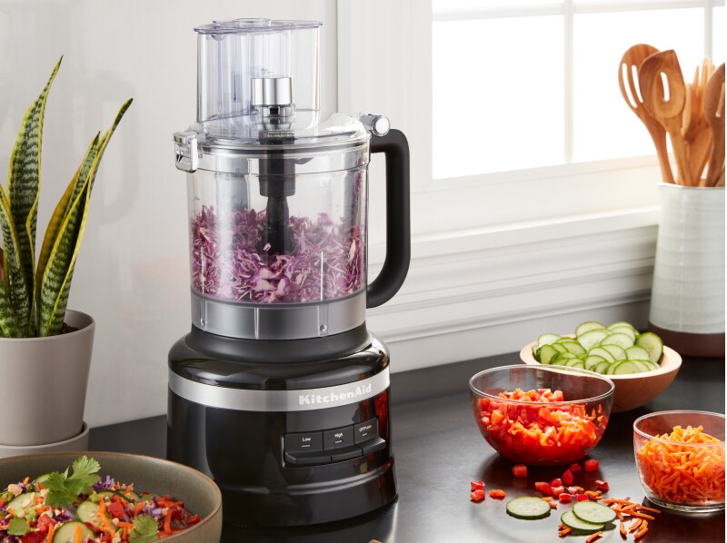 Shredded purple cabbage in a KitchenAid® food processor on a kitchen counter next to other shredded vegetables Shredded purple cabbage in a KitchenAid® food processor on a kitchen counter next to other shredded vegetables