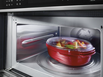 Covered bowl of vegetables in a microwave
