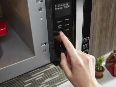 Person pushing button on a microwave