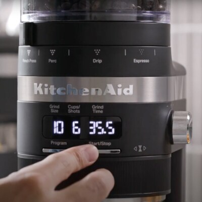 Hand selecting a dosage setting on a burr grinder