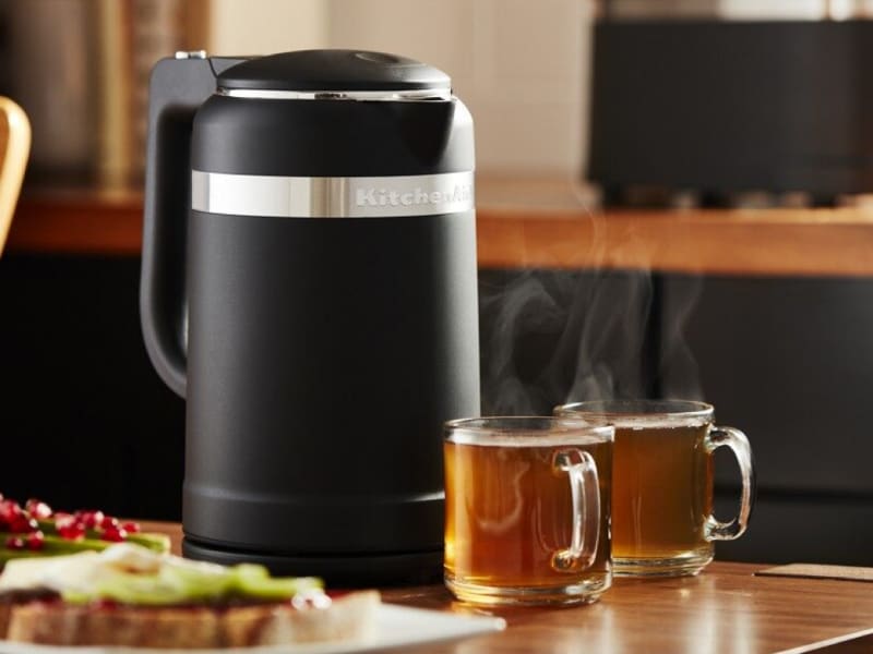 Black KitchenAid® electric tea kettle on table with glasses of tea. Black KitchenAid® electric tea kettle on table with glasses of tea.