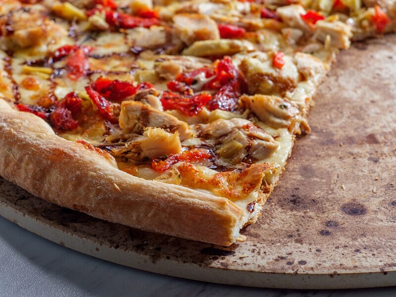 A cooked pizza on a pizza stone