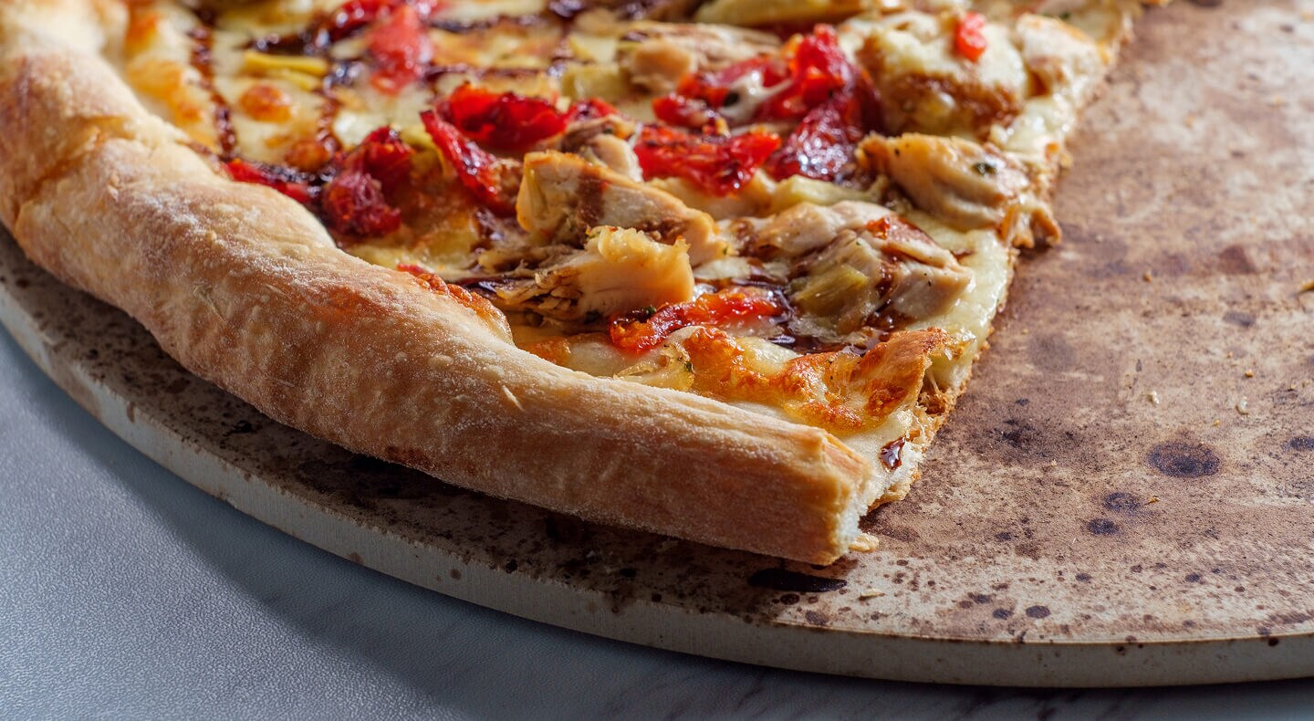 A cooked pizza on a pizza stone