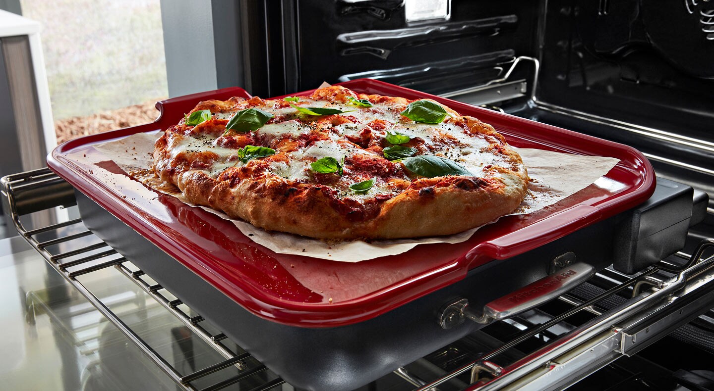 A pizza cooking on a pizza stone in an oven