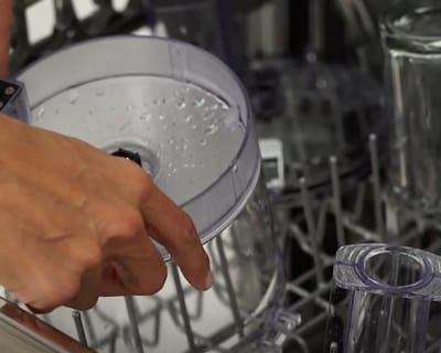Person placing food chopper bowl in dishwasher rack