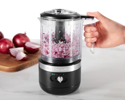 Person holding black food chopper with minced purple onion inside