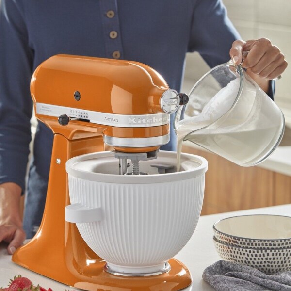 Person pouring cream into a KitchenAid® Ice Cream Maker Attachment
