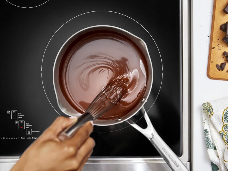 Person melting chocolate on an electric cooktop
