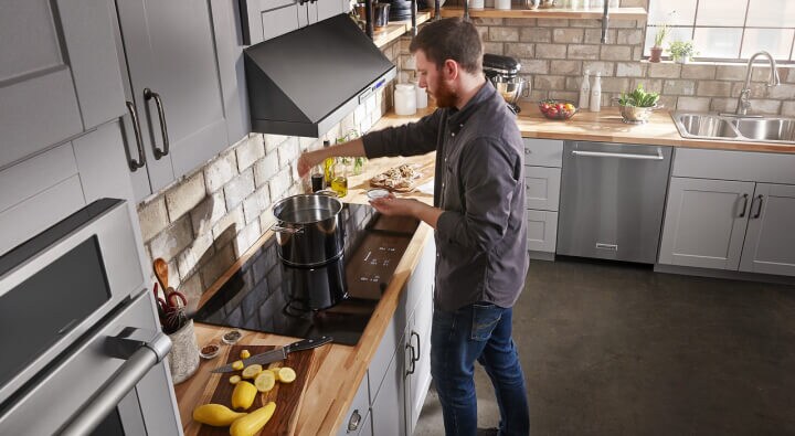 A man cooks in his kitchen using his electric cooktop