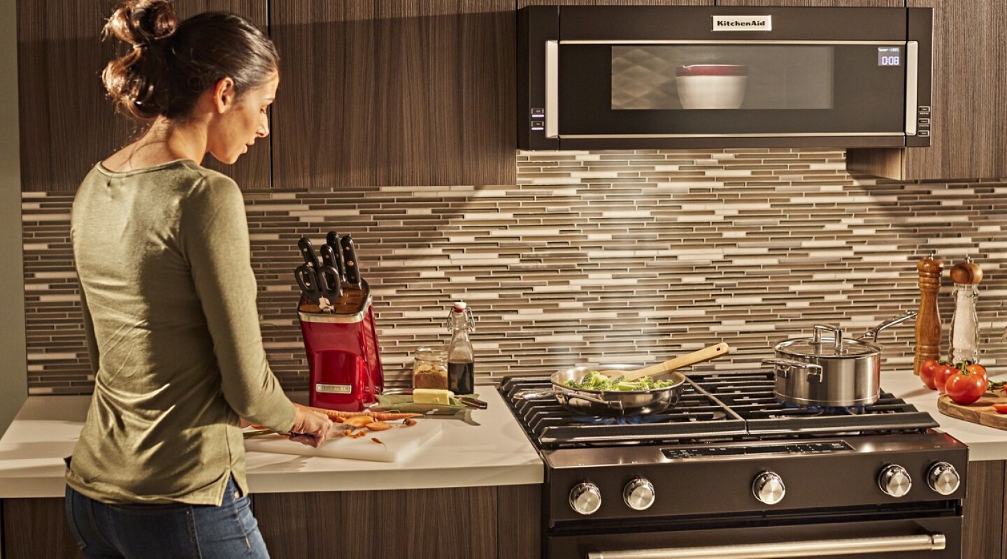 Person cooking in a kitchen with KitchenAid® appliances