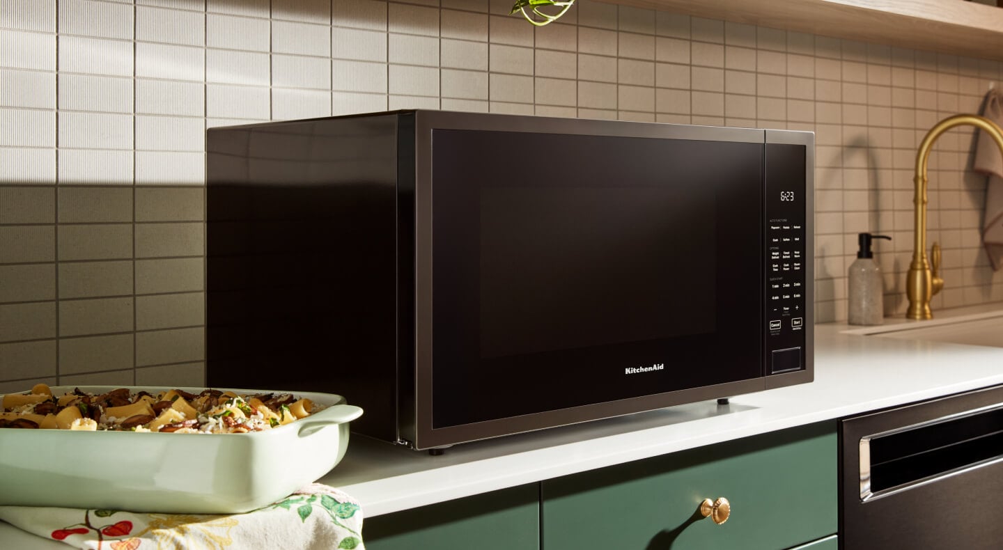 Black KitchenAid® countertop microwave above green cabinetry Black KitchenAid® countertop microwave above green cabinetry