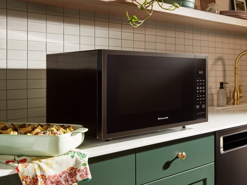 Black KitchenAid® countertop microwave above green cabinetry Black KitchenAid® countertop microwave above green cabinetry