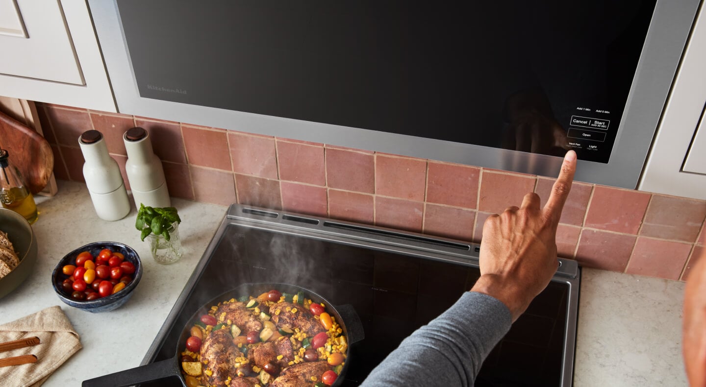 Person selecting settings on a built-in, over-the-range microwave Person selecting settings on a built-in, over-the-range microwave