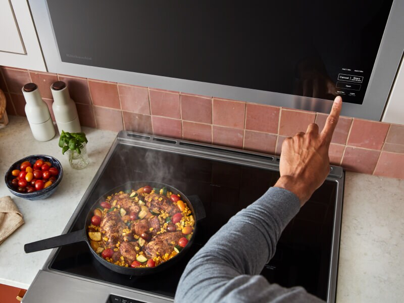 Person selecting settings on a built-in, over-the-range microwave Person selecting settings on a built-in, over-the-range microwave