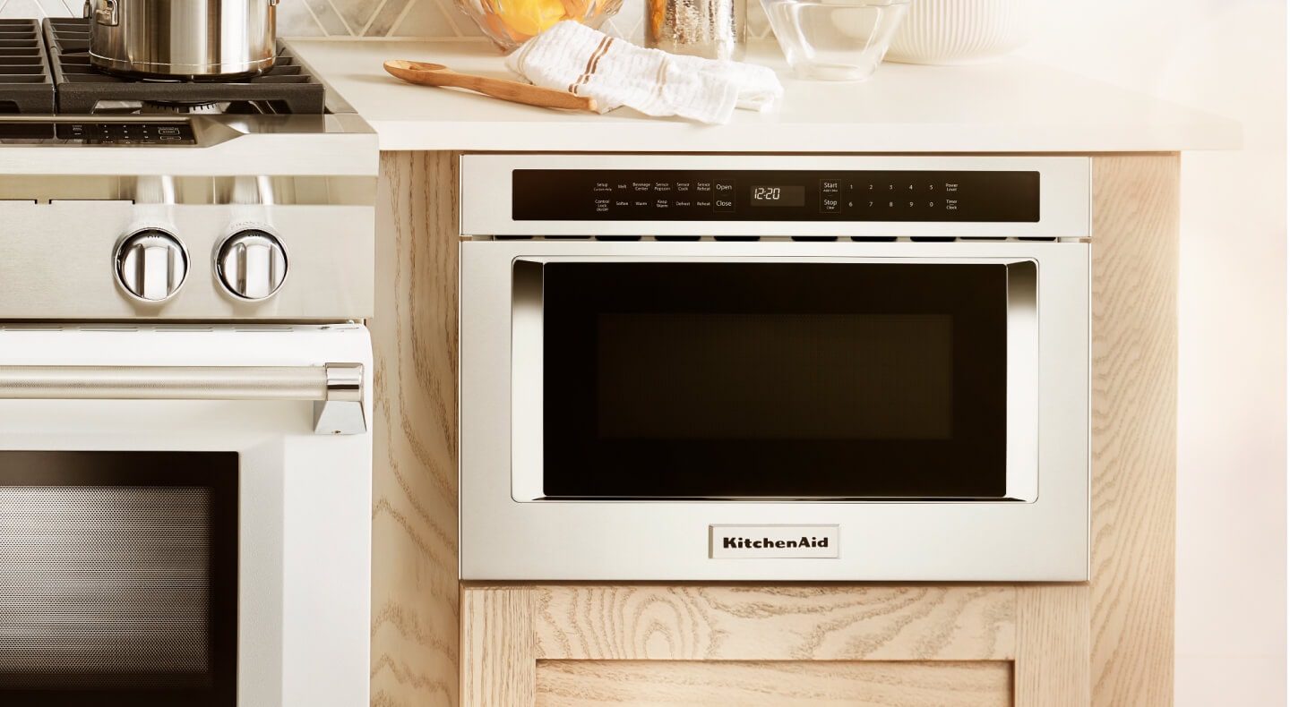 Built-in KitchenAid® microwave next to a stainless steel range Built-in KitchenAid® microwave next to a stainless steel range