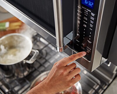 Person pressing “open” button on microwave