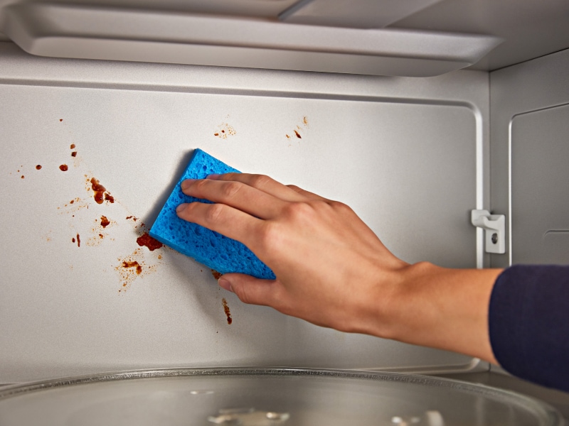 Person cleaning inside of microwave