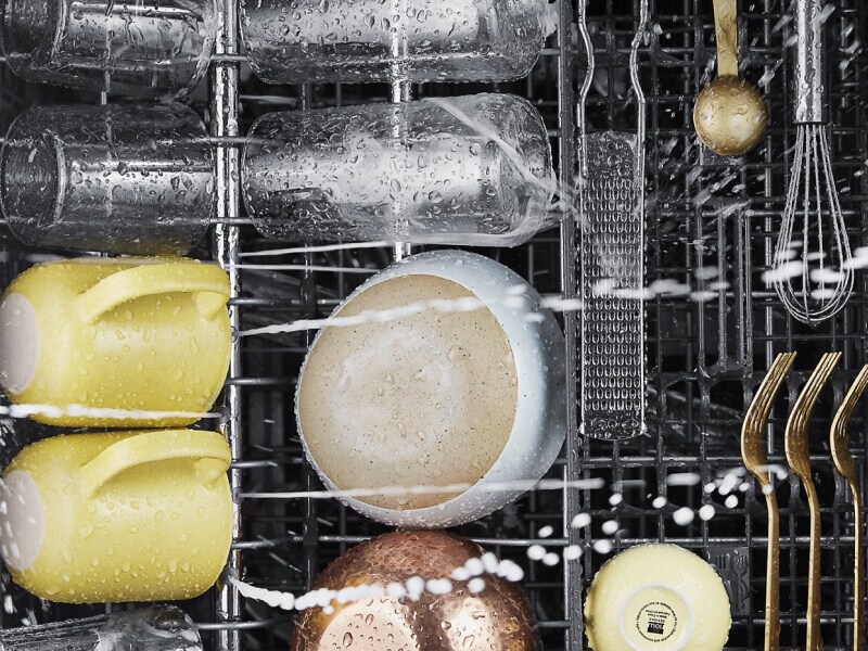Cups, bowls and utensils being washed in a dishwasher