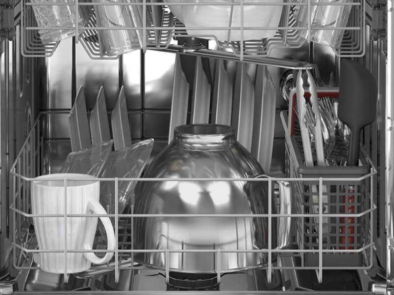Clean white plates, cups and mixing bowls inside a dishwasher