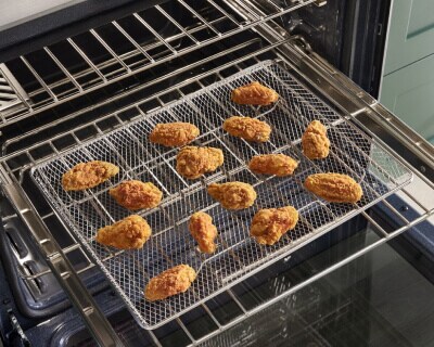 Chicken fingers on an air fry pan resting on an oven rack inside the range