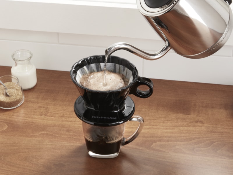 Boiled water from electric kettle being added to coffee grounds in pour over filter