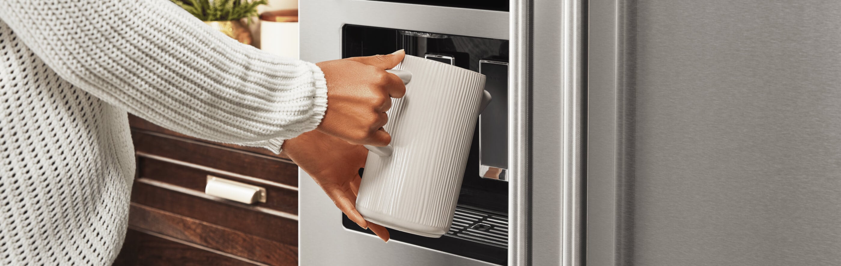 A person filling up a container at their refrigerator’s exterior ice and water dispenser