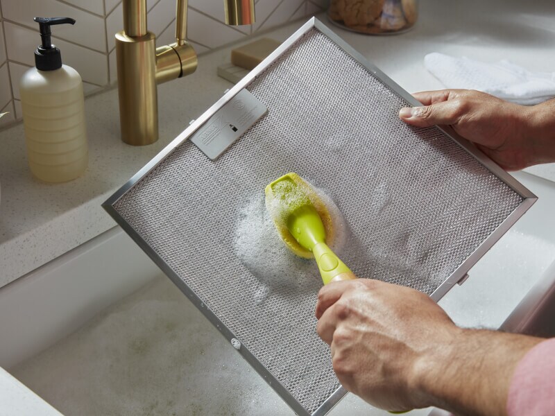 A person cleaning a grease screen