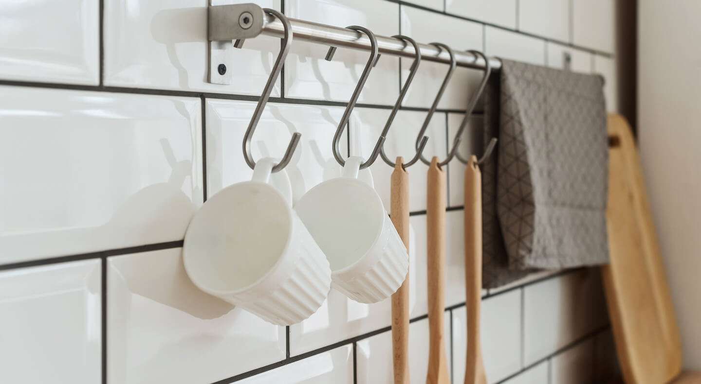 Mugs and wooden mixing spoons hanging from hooks on a rod Mugs and wooden mixing spoons hanging from hooks on a rod