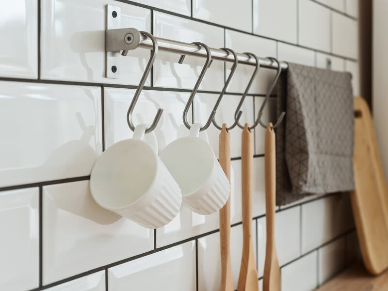Mugs and wooden mixing spoons hanging from hooks on a rod Mugs and wooden mixing spoons hanging from hooks on a rod