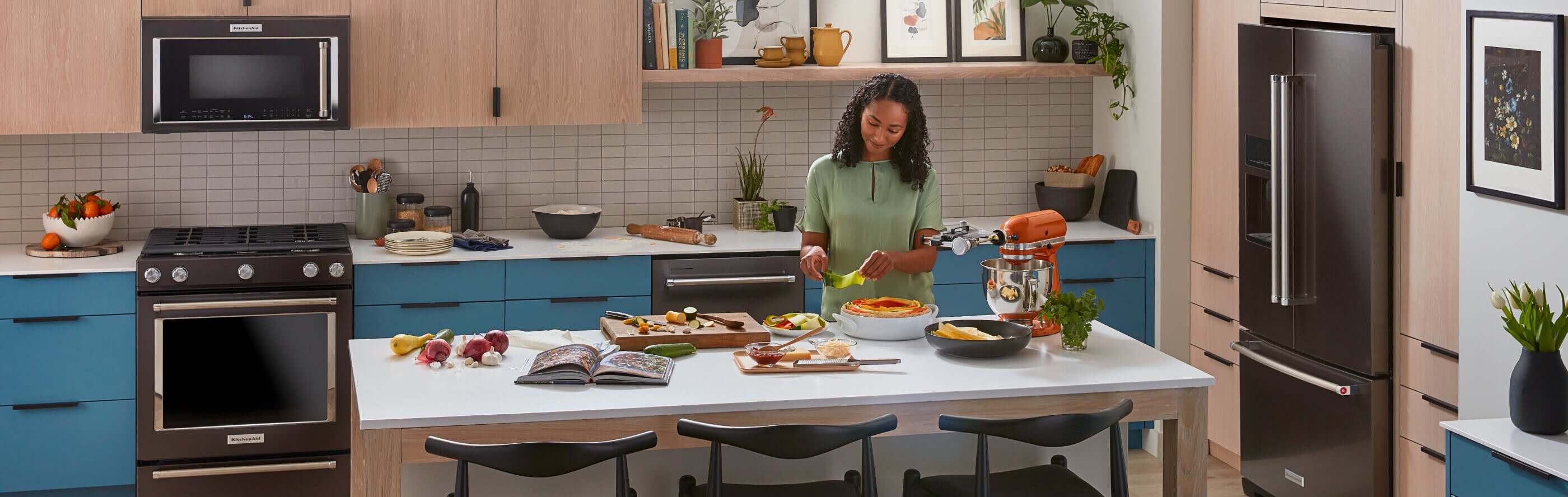 Person preparing food in a kitchen with KitchenAid® appliance suite